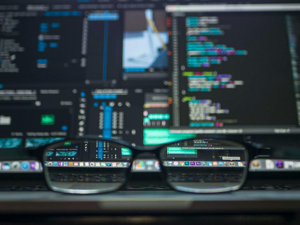 Eyeglasses reflecting computer code on a monitor, ideal for technology and programming themes